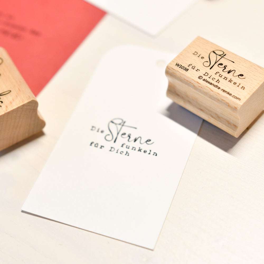 Ein gestempelter Anhänger und Holzstempel mit Stempelgummi von Alexandra Renke zeigen "Die Sterne funkeln für Dich" auf einer weißen Fläche, ideal für Ihre Papierprojekte.