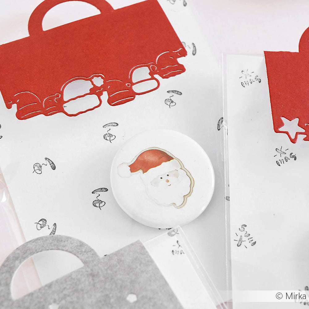 Runde Anstecknadel mit einem Weihnachtsmanngesicht, umgeben von festlich handdekorierten Geschenktüten in Rot, Weiß und Grau - jedes Design ist mit dem charmanten Alexandra Renke Akzent-Stempel versehen, der für zusätzliches Weihnachtsflair sorgt.