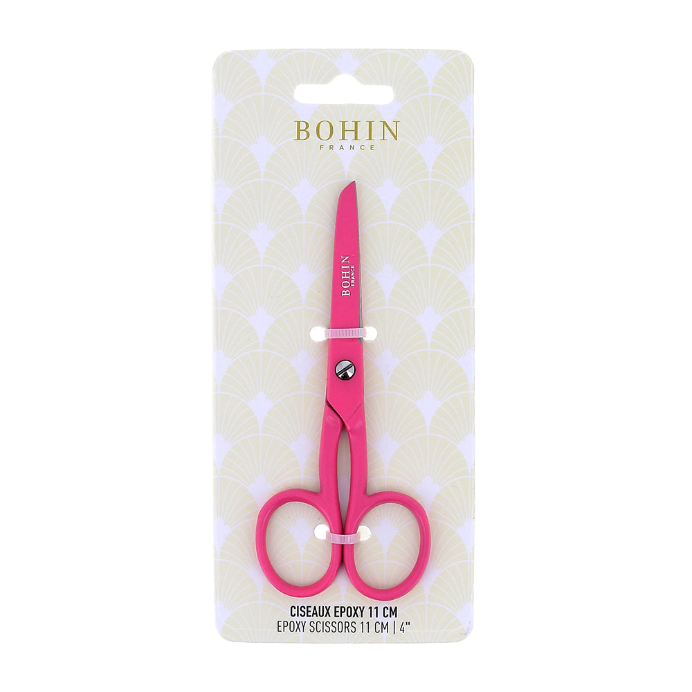 Rosa Epoxid-Schere von BOHIN France in der Verpackung, 11 cm lang, abgebildet vor einem gemusterten Hintergrund. Mit Epoxidbeschichtung für verbesserten Korrosionsschutz und dauerhafte Schnittpräzision.