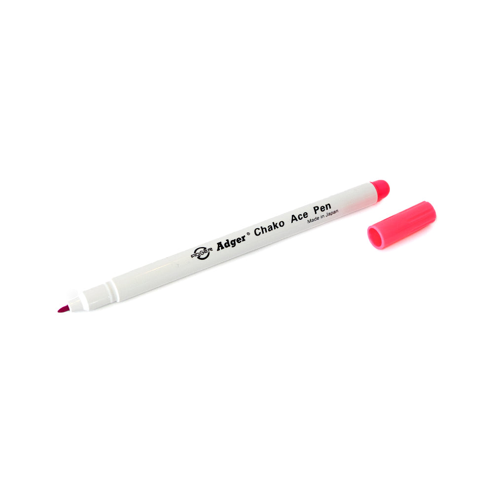 Ein weißer „Chako Ace“-Stift von BOHIN France, der üblicherweise als wasserlöslicher Stift und Markierstift zum Übertragen von Stickvorlagen verwendet wird, liegt mit abgenommener rosa Kappe auf einem weißen Hintergrund.