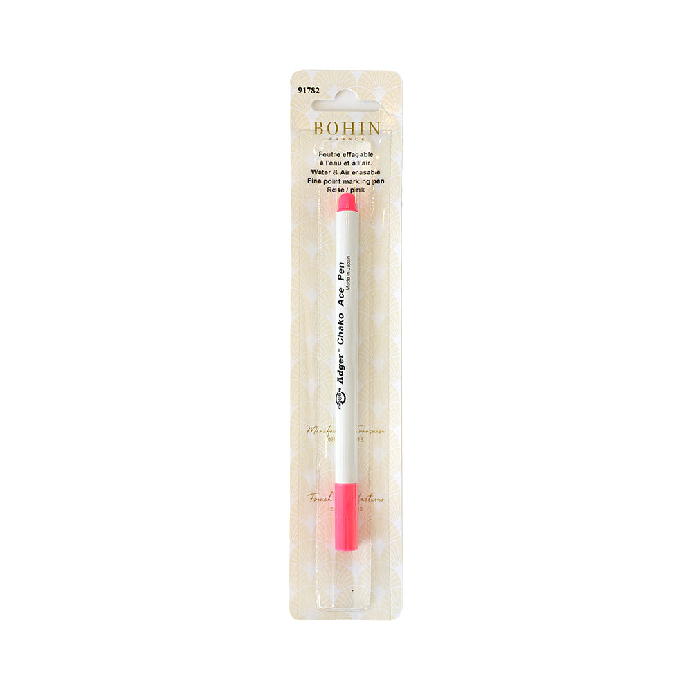 Ein abwischbarer rosa Markierungsstift (Markierungsstift Nähen) von BOHIN France in einer Kunststoffverpackung mit beigem gemustertem Hintergrund, ideal als Patchwork-Zubehör für präzise und vorübergehende Markierungen auf Stoff.