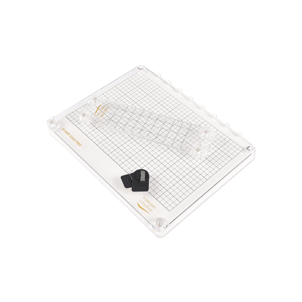 Die Vaessen Clear Stamp Easy Pro Stempelplattform verfügt über ein Gitter, ein Lineal und zwei schwarze Magnete auf einer weißen Basis. Perfekte Stempelhilfe für präzise Ausrichtung und gleichmäßigen Druck auf die Stempelfläche bei Ihren Bastelprojekten.