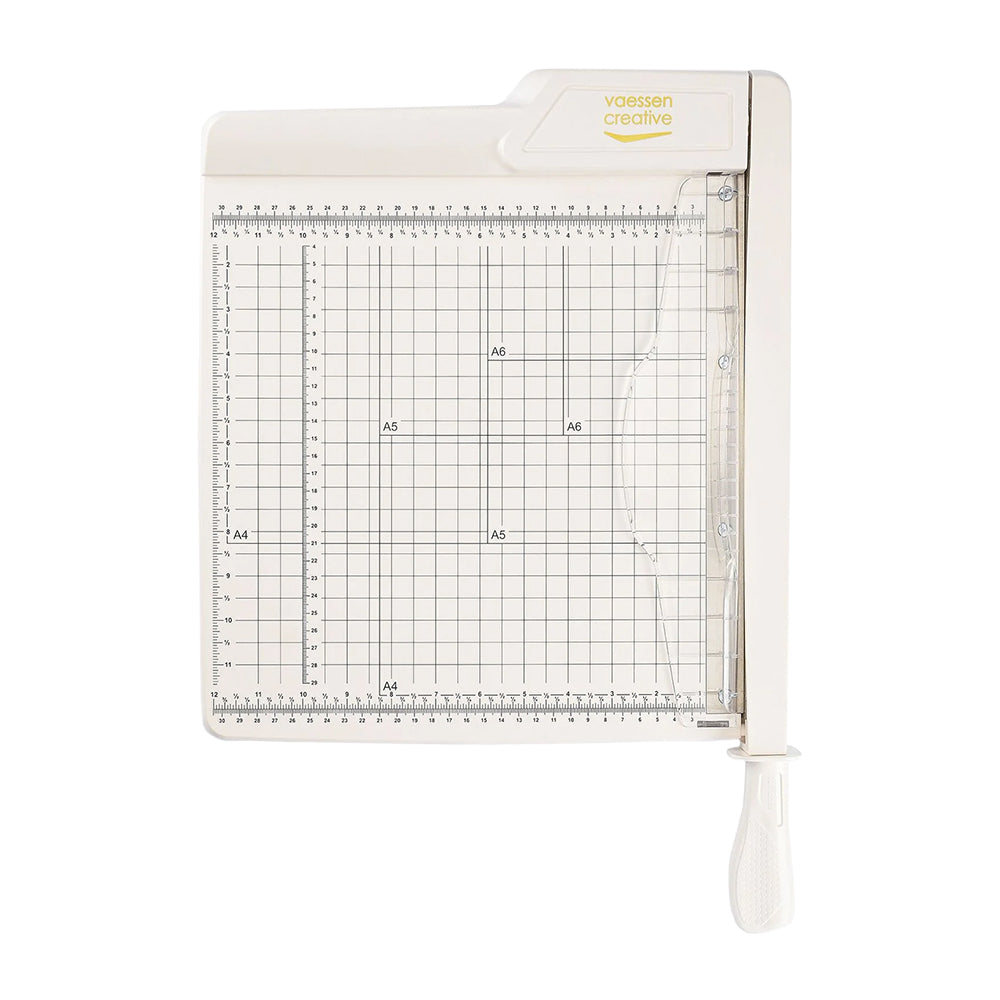 Der Vaessen Guillotine-Papierschneider verfügt über ein Gitter, ein Lineal, einen weißen Griff und "Vaessen Creative" in gelber Schrift.
