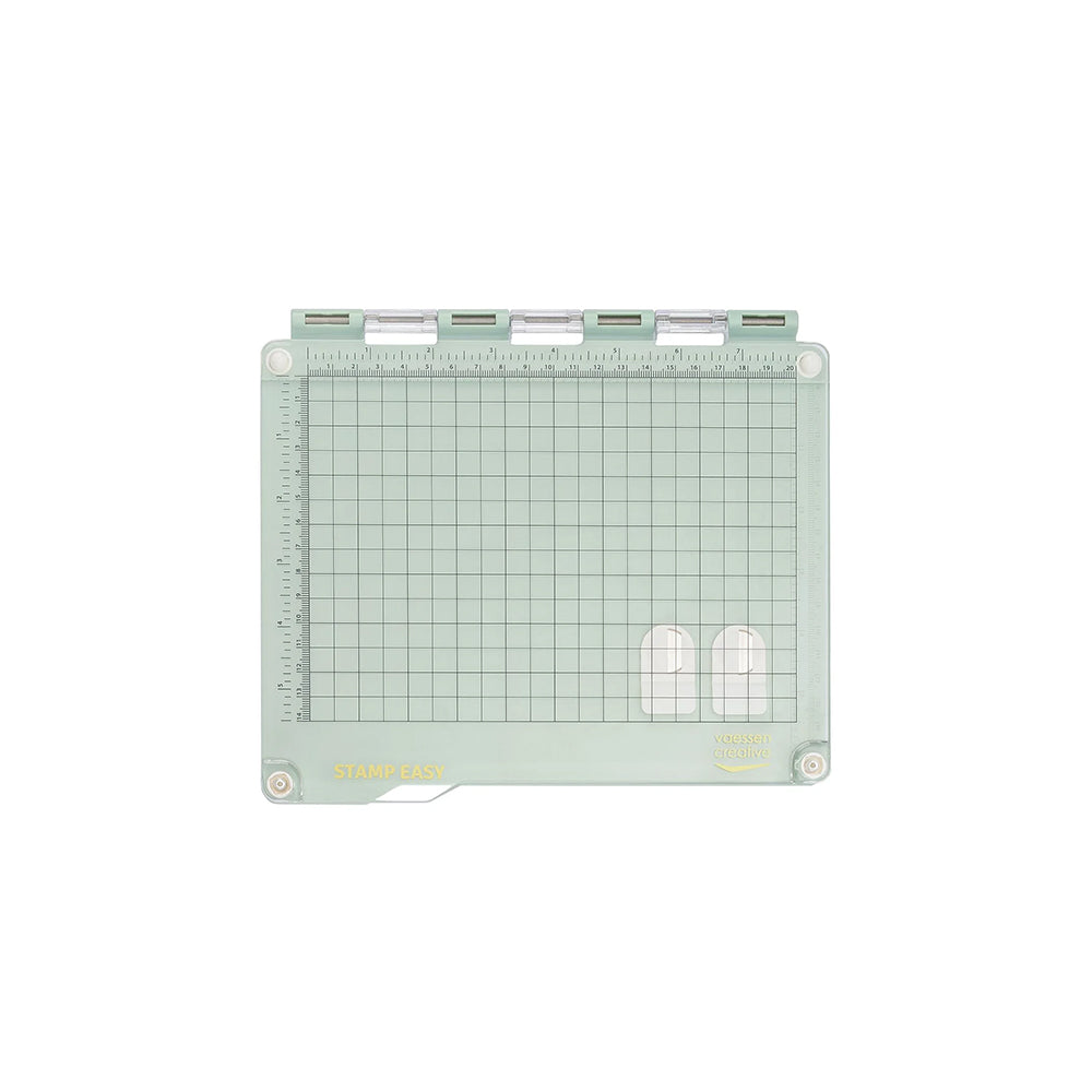 Die grüne Kunststoff-Stempelplatte von Vaessen verfügt über Rasterlinien, Linealmarkierungen und Scharniere an der Oberkante - ideal als Stamp Easy Stempelwerkzeug für die präzise Platzierung von Klarsichtstempeln.