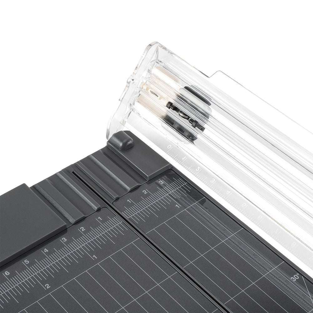 Nahaufnahme eines Vaessen-Papierschneiders mit transparentem Falzlineal und Schneidemesser auf einer schwarzen Gitteroberfläche.