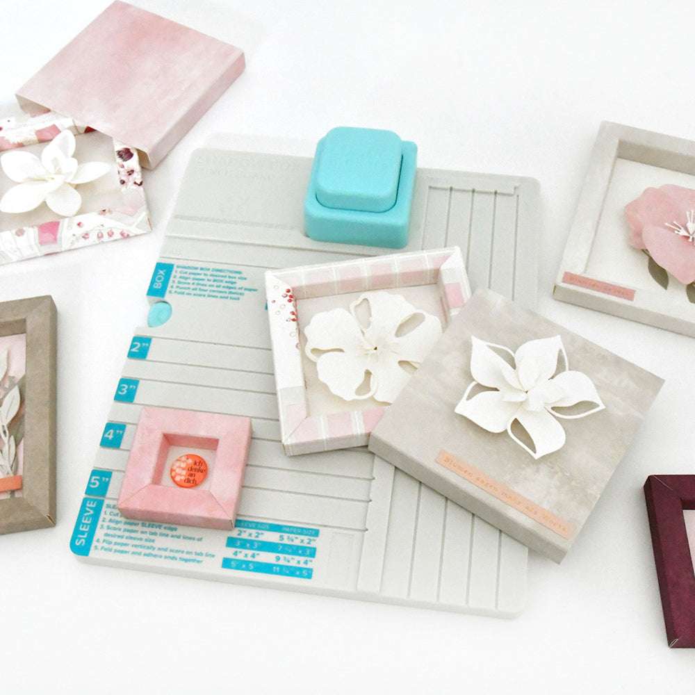Das We R Memory Keepers Falzbrett mit Stanzwerkzeug ist ideal zum Basteln von Papier-Schattenboxen und handgefertigten, mit Papierblumen verzierten Geschenkboxen.